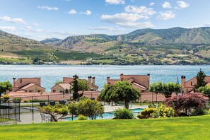 Ein Anwesen am Seeufer mit Schwimmbad, Tennisplatz und Blick auf See und Hügel.