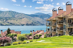 Ein mehrgeschossiges Hotel mit Balkonen mit Blick auf einen See und Berge.
