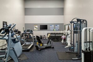Een fitnessruimte met loopbanden, krachtapparaten en gewichten.