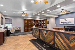 Un mostrador de recepción con un diseño de tablero de ajedrez de madera, una estantería llena de libros y un cartel que dice 'WORLDMARK BY WYNDHAM'.