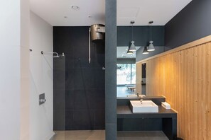 Un baño moderno con ducha, lavamanos y espejo.