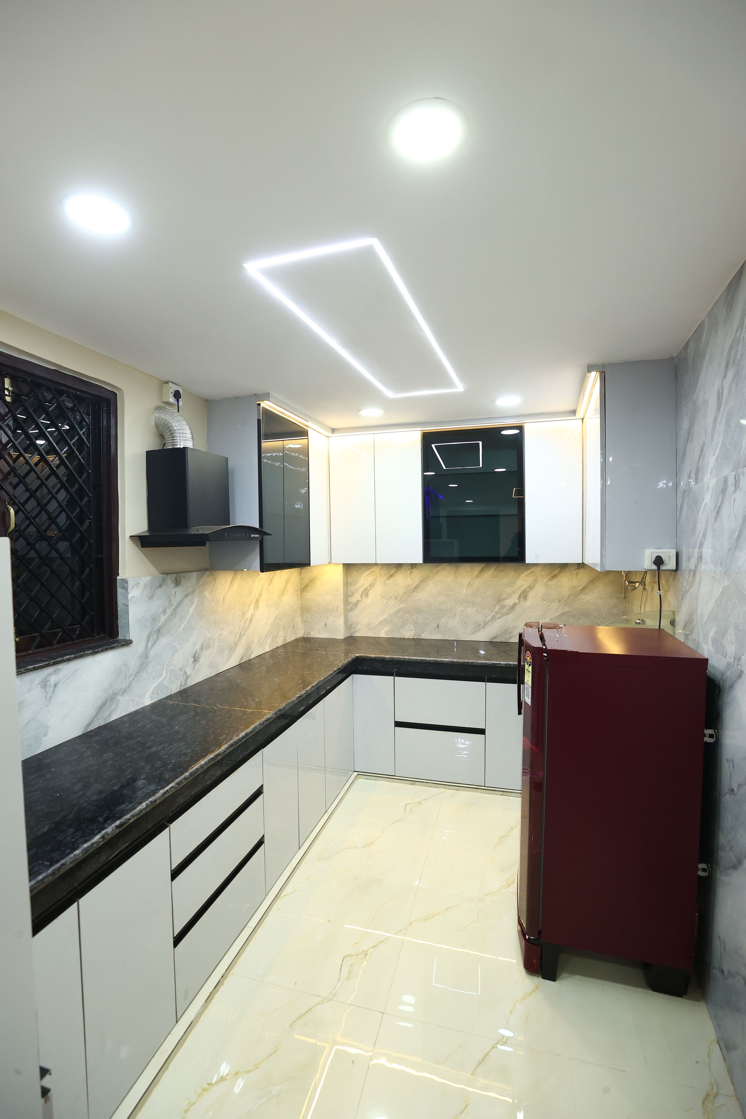Una cocina moderna con encimera de mármol, armarios empotrados y un refrigerador rojo.