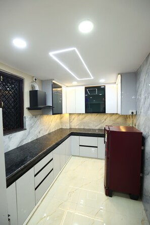 Una cocina moderna con encimera de mármol, armarios empotrados y un refrigerador rojo.