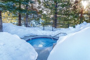 Ein Pool, umgeben von Schnee, mit einem Zaun und Bäumen im Hintergrund.