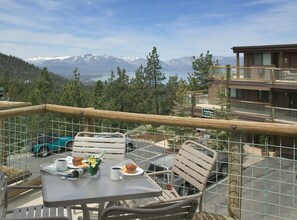 Ein Balkon mit Tisch für zwei Personen, mit Blick auf eine gebirgige Landschaft.