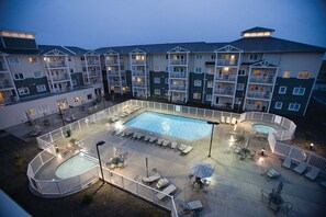 Une cour d’hôtel avec une piscine, des chaises longues et un espace délimité par une clôture.