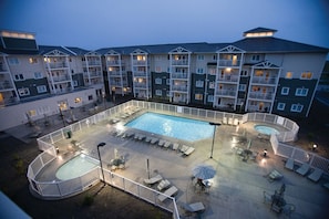 Une cour d’hôtel avec une piscine, des chaises longues et un espace délimité par une clôture.