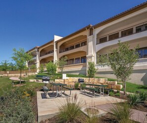 Un edificio de varios pisos con mesas al aire libre y un patio ajardinado.
