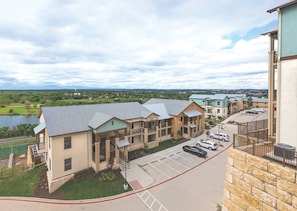 A multi-story residential building with a parking lot and a view of a lake. - Marble Falls | Group Outdoor Retreat | Pool + Lake | 2BR (Marble Falls)