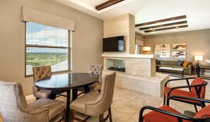 A modern living room with a fireplace, a flat-screen TV, and a dining area with wicker chairs. - Marble Falls | Family Lake Retreat | Pool | 2BR (Marble Falls)