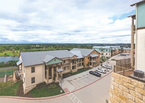 A multi-story residential building with a parking lot and a view of a lake. - Marble Falls | Premium Lake Retreat | Pool + Lake | 2BR (Marble Falls)