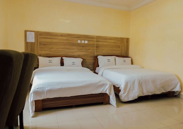 Una habitación de hotel con dos camas individuales, un cabecero de madera y una silla.