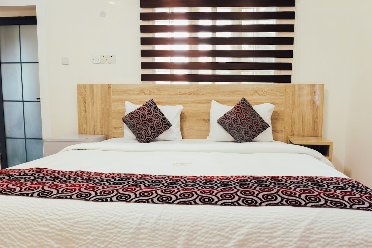 A bed with a wooden headboard, two patterned pillows, and a patterned bedspread.