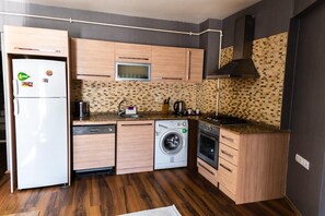 Cozinha compacta equipada com frigorífico, micro-ondas, máquina de lavar loiça, máquina de lavar roupa e forno.