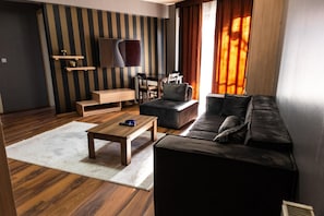 Uma sala de estar moderna com sofá, mesa de centro, televisão e parede listrada.