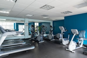 Ein Fitnessraum mit Laufbändern, Crosstrainern und stationären Fahrrädern.