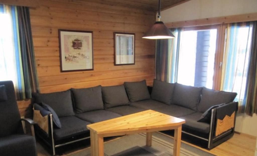 A room with a wooden wall, a sofa, a table, and curtains.