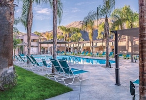 A pool area with lounge chairs, palm trees, and a mountain backdrop. - Palm Springs | Group Desert Retreat | Pool + Hot Tub | 2BR (Palm Springs)