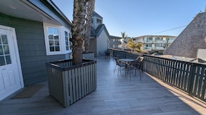 A covered patio with a seating area, a tree planter, and a view of neighboring buildings.