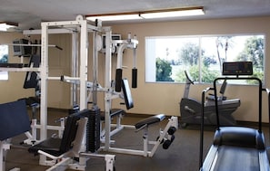 A gym with exercise equipment, a treadmill, and a window with a view of trees. - Palm Springs | Couples Desert Retreat | Pool + Hot Tub (Palm Springs)