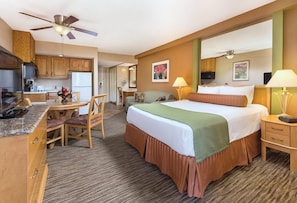 A hotel room with a bed, desk, chair, kitchenette, and a ceiling fan. - Palm Springs | Couples Desert Retreat | Pool + Hot Tub (Palm Springs)