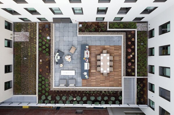 Una terraza en la azotea con zona de estar, una mesa de comedor y macetas.