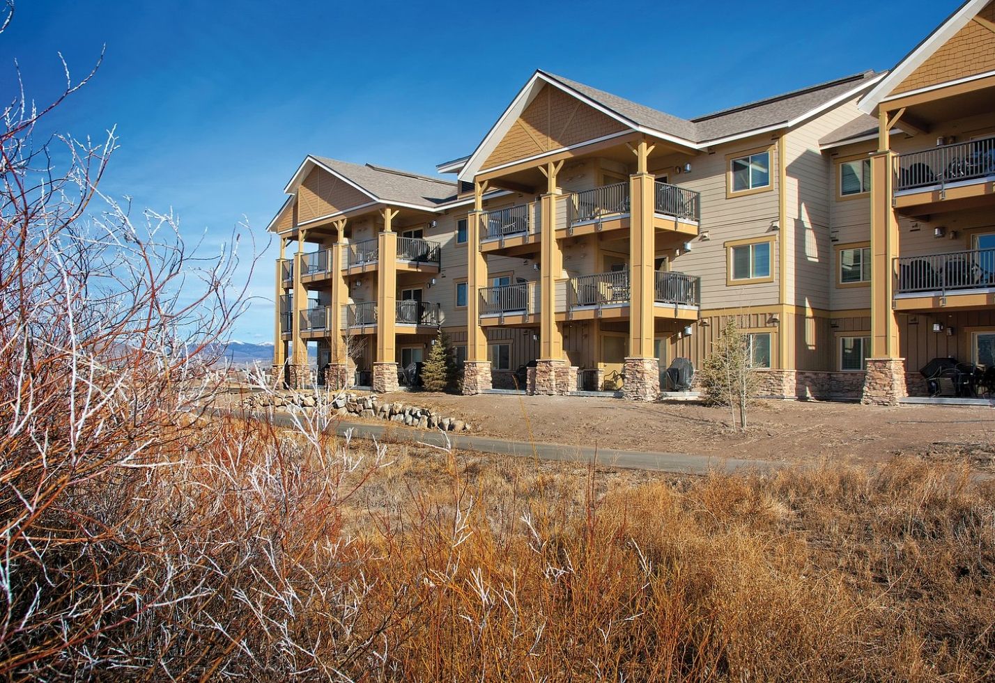 A multi-story hotel with balconies, stone pillars, and a view of the surrounding landscape.