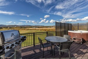 Una terraza con una parrilla, un jacuzzi y una mesa con sillas.