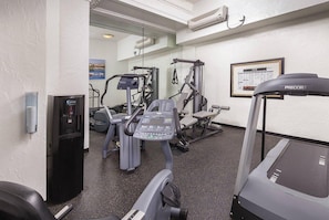 Ein Fitnessstudio mit Laufbändern, Kraftgeräten und einem Wasserspender.