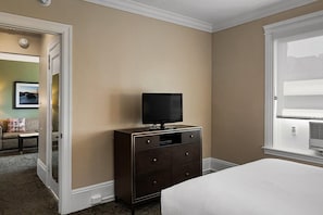 Ein Hotelzimmer mit Bett, Schminktisch, Fernseher und einem Fenster mit Jalousien.