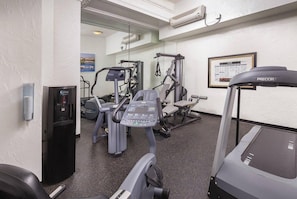 Une salle de sport équipée de tapis de course, d’appareils de musculation et d’un distributeur d’eau.