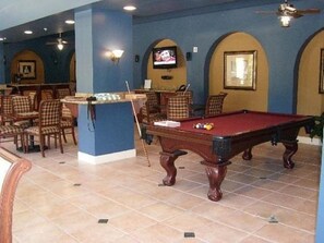 A pool table with chairs, a bar area, and a television mounted on the wall. - Santa Barbara | Romantic Beach Retreat | Pool + Beach (Pompano Beach)