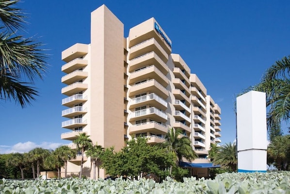 A multi-story hotel with balconies, palm trees, and a clear sky. - Santa Barbara | Romantic Beach Retreat | Pool + Beach (Pompano Beach)