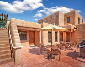 Une terrasse avec des meubles d’extérieur, un barbecue et une clôture en bois.