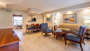 A hotel room with a dining area, a sofa, armchairs, a coffee table, and a TV. - Pompano Beach | Tranquil Poolside Stay | Pool + Beach (Pompano Beach)