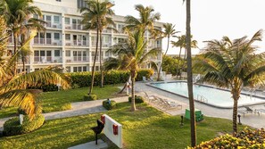 Een hotel met een zwembad, palmbomen en een verzorgd gazon.