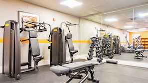 A gym with various exercise machines, a bench, and a mirror. - Pompano Beach | Relaxed Poolside Stay | Pool + Beach (Pompano Beach)