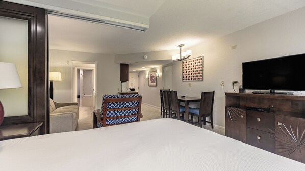 A hotel room with a bed, a desk, a chair, a television, and a wall-mounted light fixture. - Pompano Beach | Relaxed Poolside Stay | Pool + Beach (Pompano Beach)