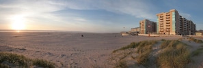 Una platja amb un gran complex arquitectònic al fons.