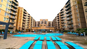 Edifici residencial de diversos pisos amb un pati central que inclou una piscina i gandules.