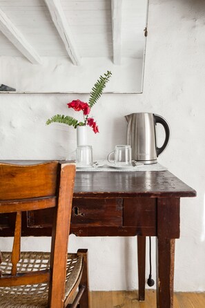 A wooden table with a metal kettle, a glass mug, and a white vase with red flowers. - Holiday home 'Dimora Dei Frati - Wundergarten' with mountain view, Wi-Fi and air conditioning (Gratteri)