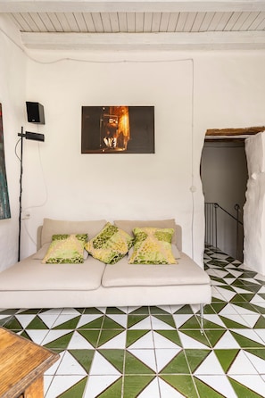 A room with a sofa, a painting, a speaker, and a patterned floor. - Holiday home 'Dimora Dei Frati - Wundergarten' with mountain view, Wi-Fi and air conditioning (Gratteri)