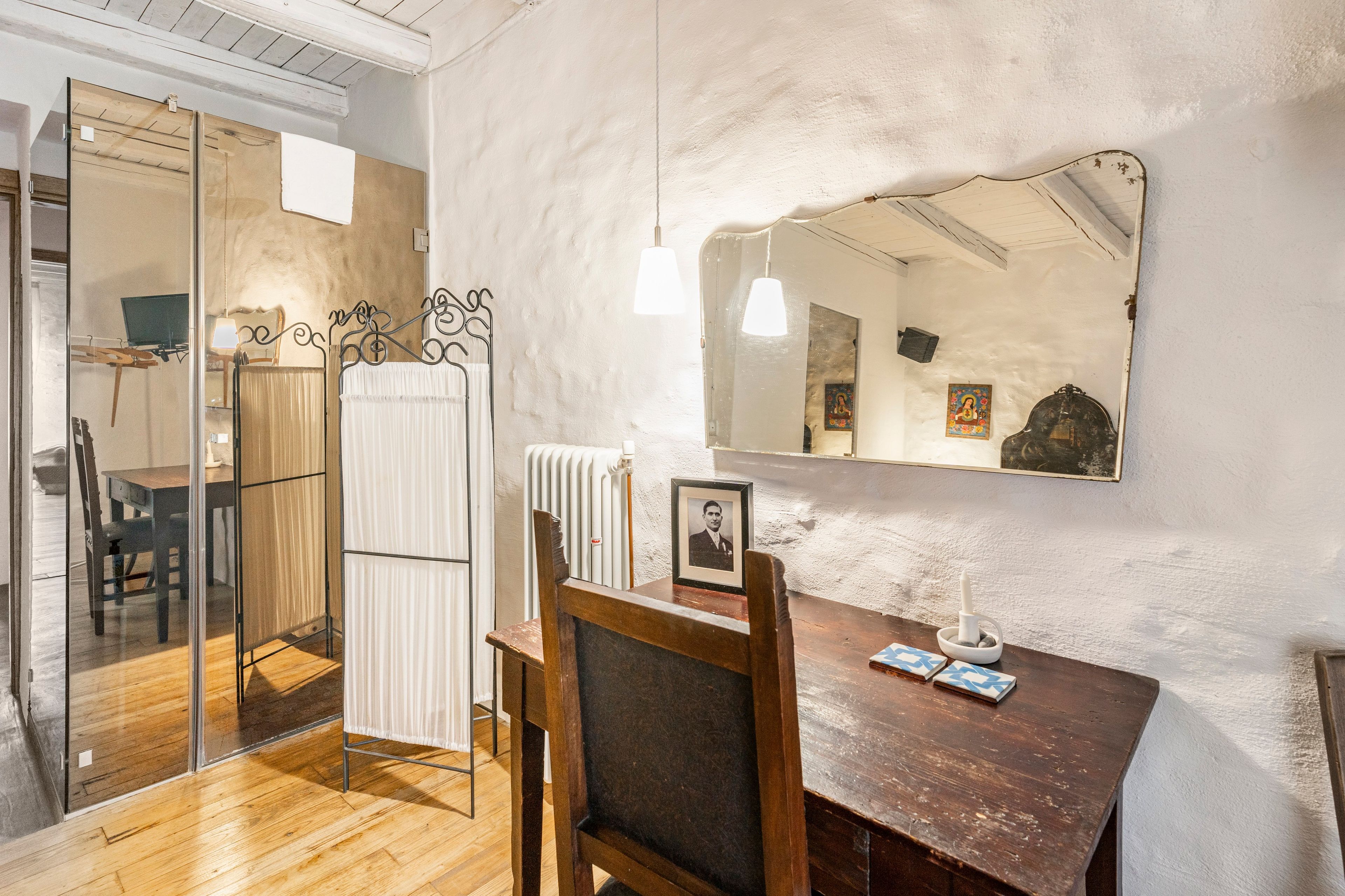 Ein Zimmer mit einem Holztisch, einem Stuhl, einem Spiegel und einer Heizung.
