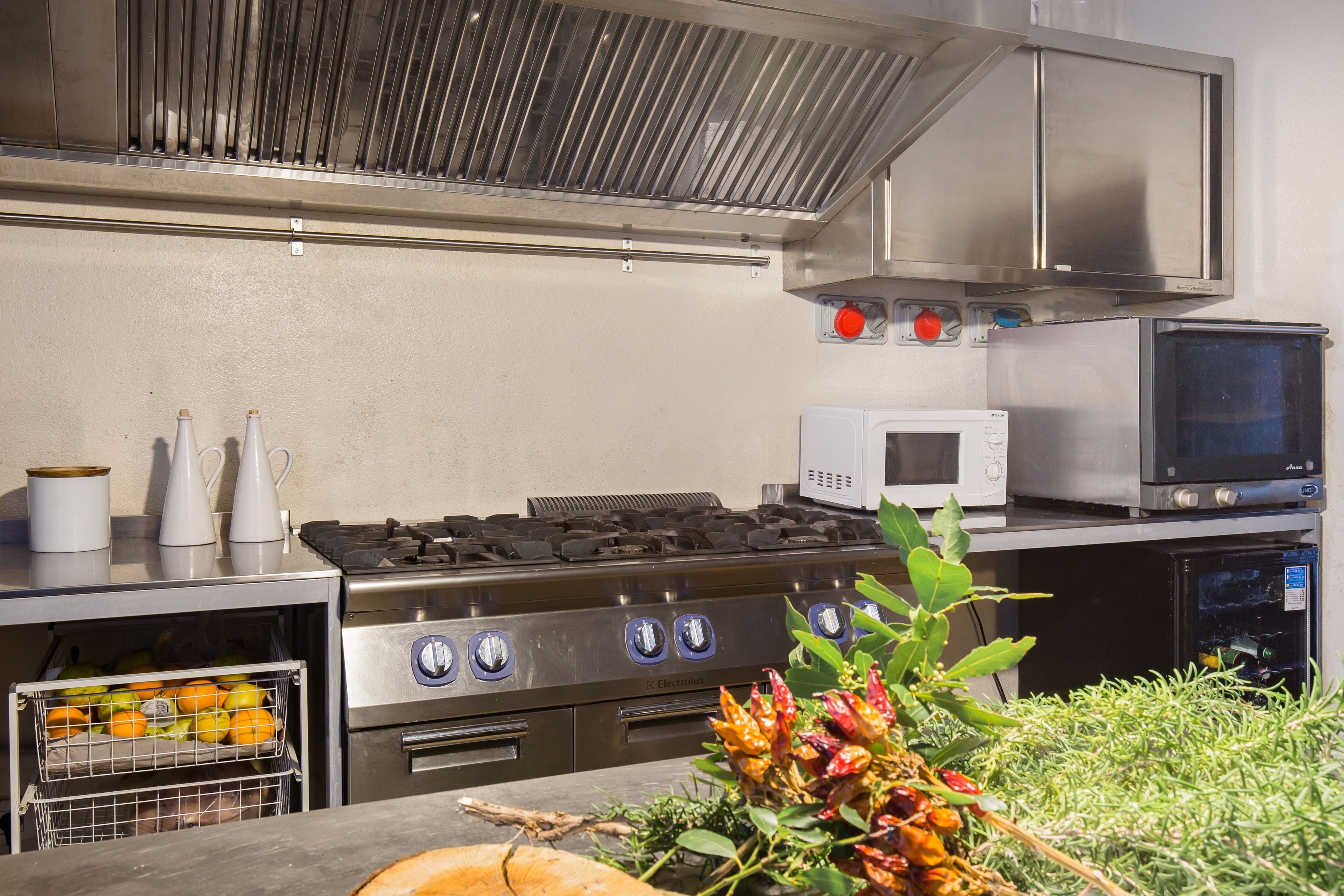 A commercial kitchen with stainless steel appliances, including a stove, microwave, and oven.