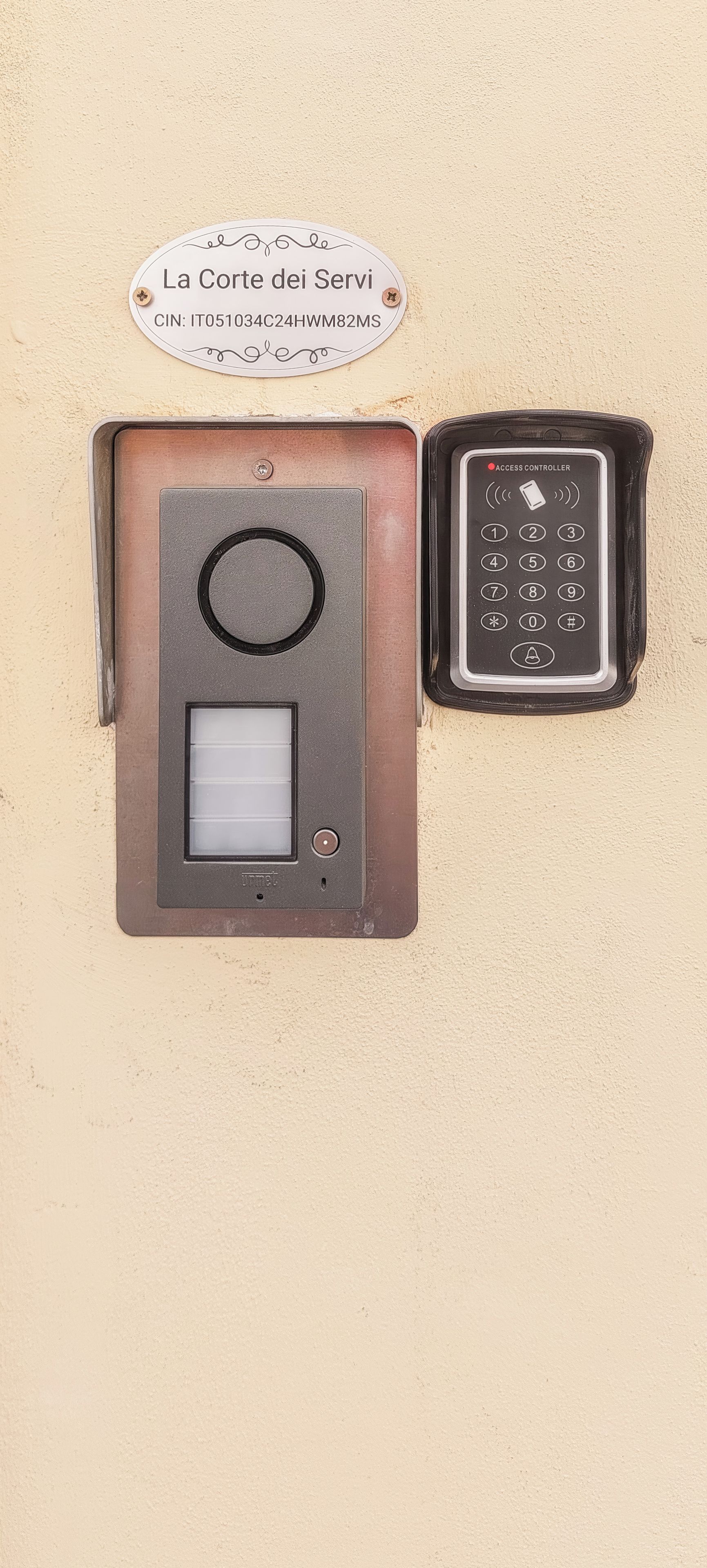 Un sistema de intercomunicación instalado en la pared, con teclado y panel de visualización, acompañado de un cartel con texto y un número CIN.