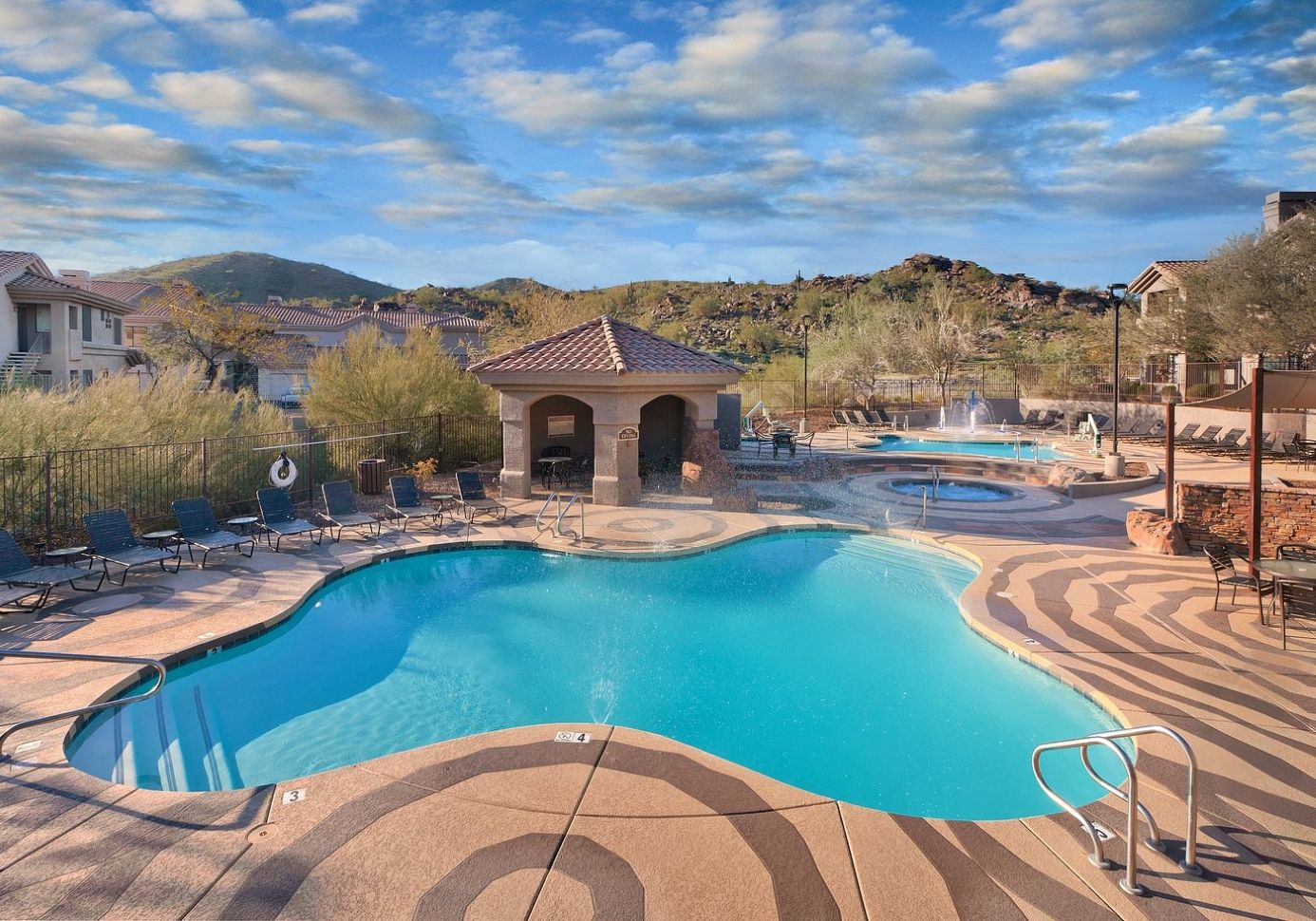 A swimming pool with lounge chairs and a small pavilion.