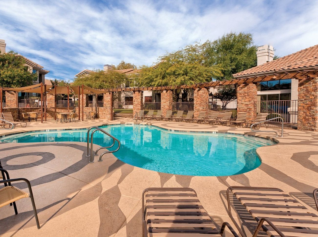 A swimming pool with lounge chairs and a covered patio area.