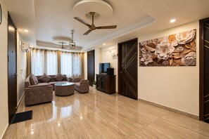 Uma sala de estar moderna com sofá, mesa de centro, televisão e um painel decorativo na parede.