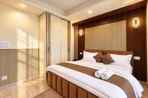 Une chambre d’hôtel moderne avec un grand lit, des panneaux de bois et un éclairage intégré.