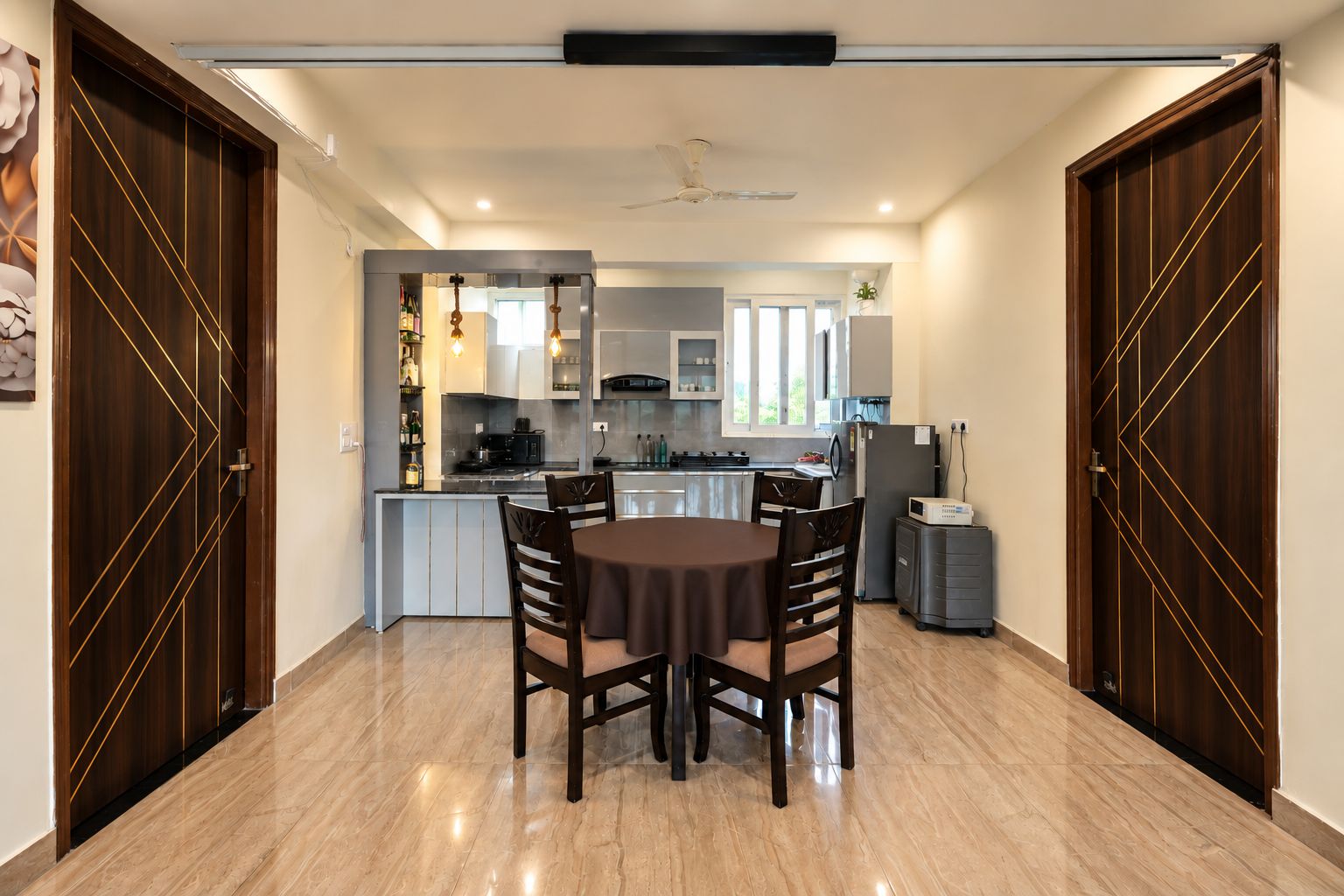 Una cucina moderna con zona pranzo, caratterizzata da un pavimento in marmo, mobili in legno e un'isola centrale.